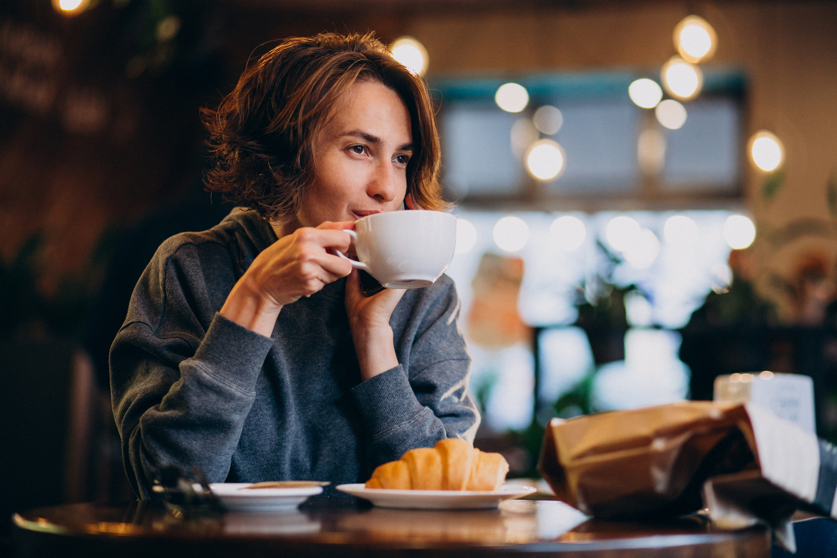 Vrouw drinkt koffie met een croissant